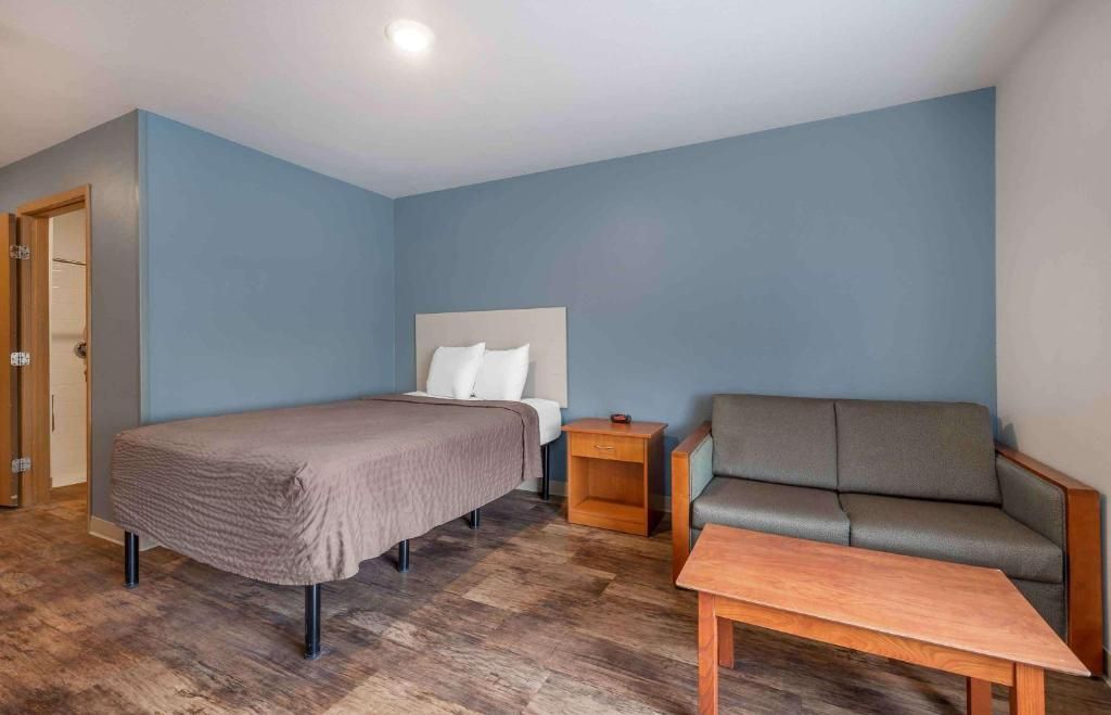 Een kamer met een bed, een slaapbank, een nachtkastje en een houten tafel.
