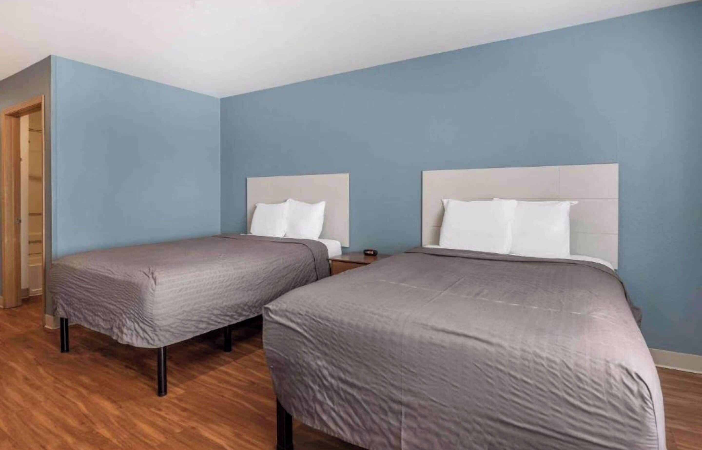 Une chambre avec deux lits, un plancher en bois et un mur bleu.