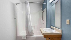 A bathroom with a shower, a sink, and a mirror. - Studio 6 Extended Stay Wichita South KS (Wichita)