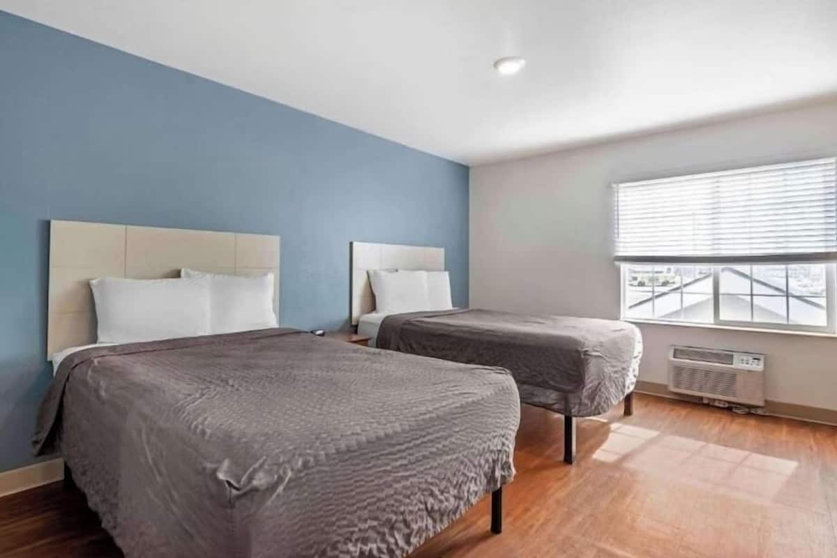 Une chambre d’hôtel avec deux lits, une grande fenêtre et un luminaire au plafond.
