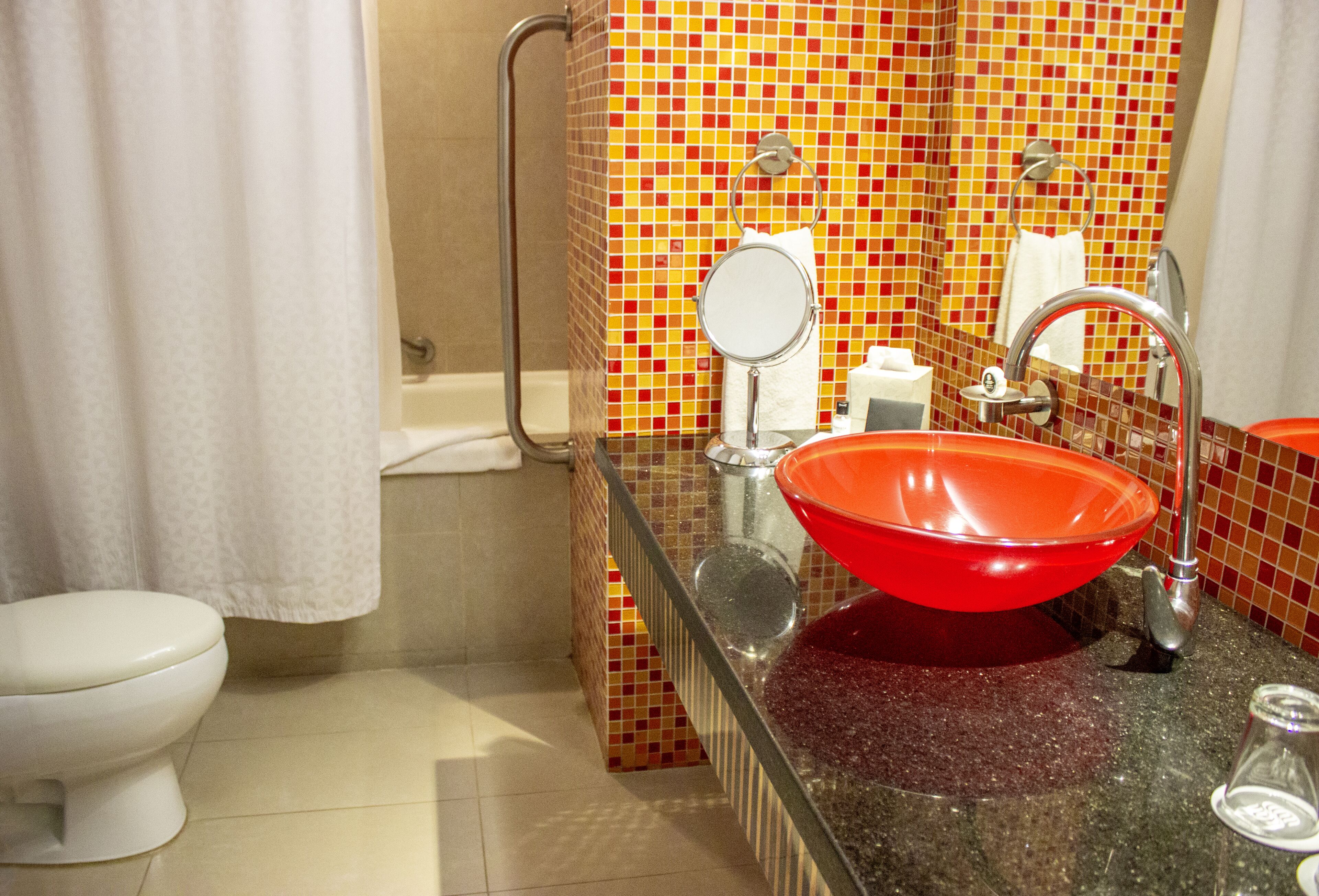 Un baño con un lavamanos rojo, un inodoro blanco y una zona de ducha.