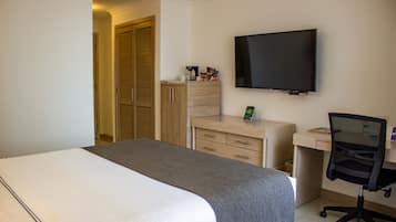 Ett hotellrum med en säng, ett skrivbord, en stol, en tv och en garderob.