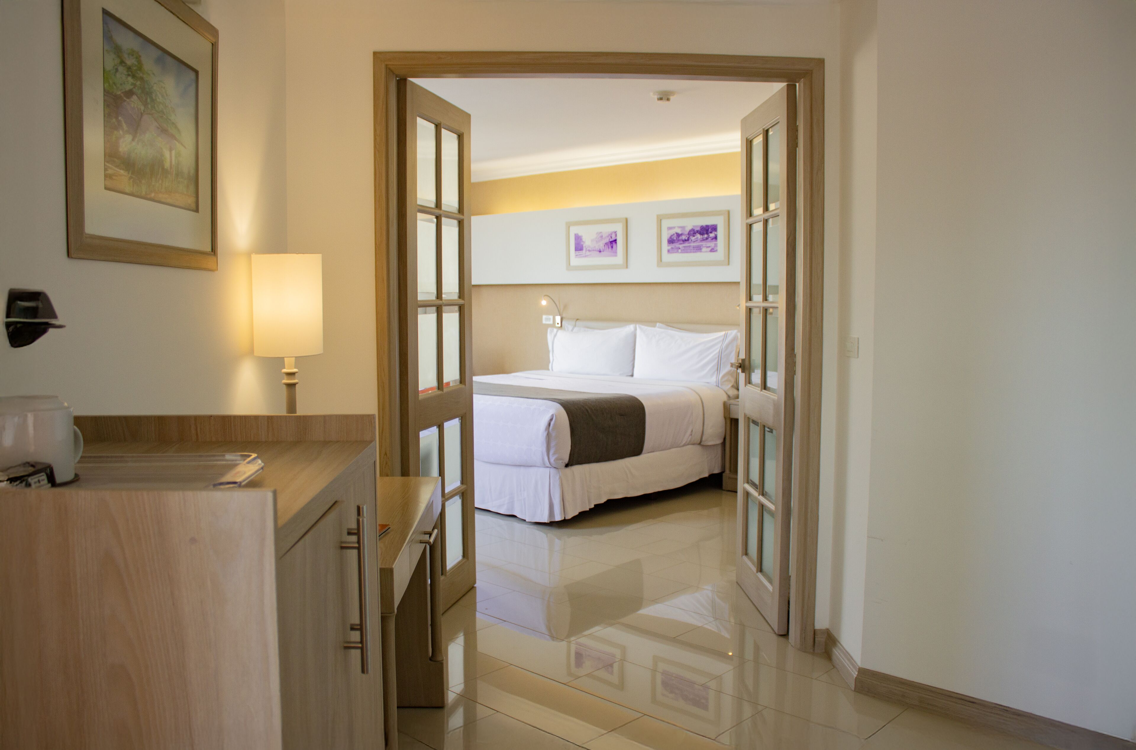 Habitación de hotel con cama, mesita de noche, lámpara y un cuadro en la pared.