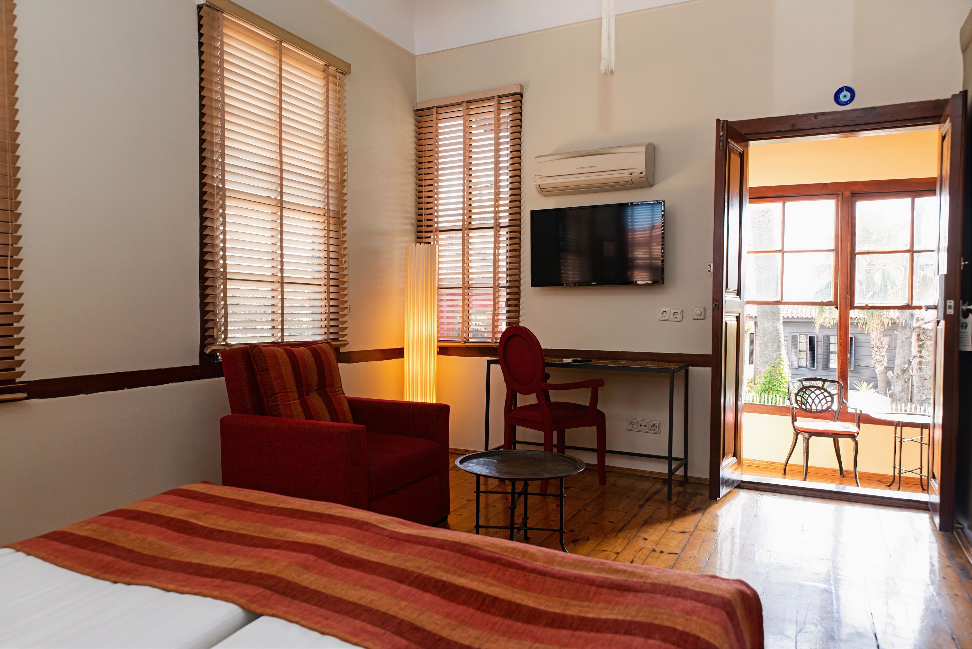 A hotel room with a bed, a desk, a chair, and a television.