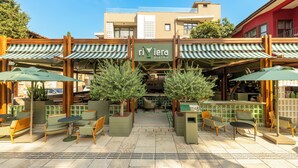 Un patio al aire libre con toldos de rayas verdes, muebles de madera y plantas en macetas.