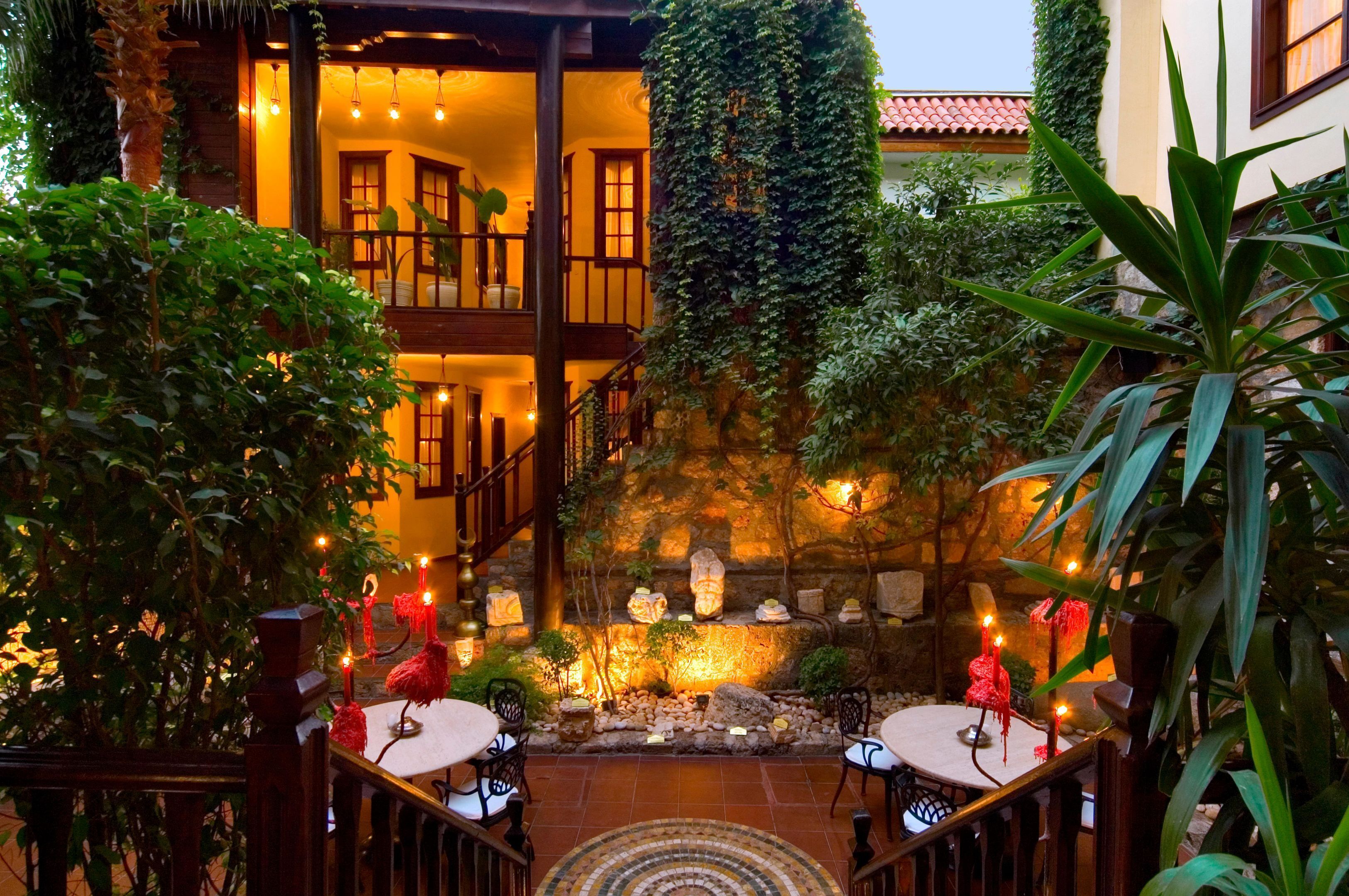 A courtyard with a stone fountain, seating areas, and a staircase leading to an upper level.