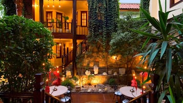 A courtyard with a stone fountain, seating areas, and a staircase leading to an upper level.