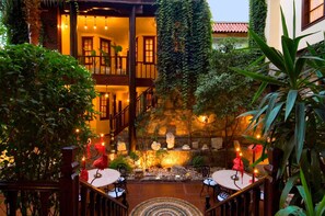 Un patio con una fuente de piedra, zonas de estar y una escalera que conduce a un nivel superior.