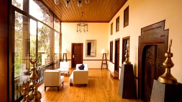 Une pièce spacieuse avec un plancher en bois, un canapé blanc, une porte en bois et une grande fenêtre.