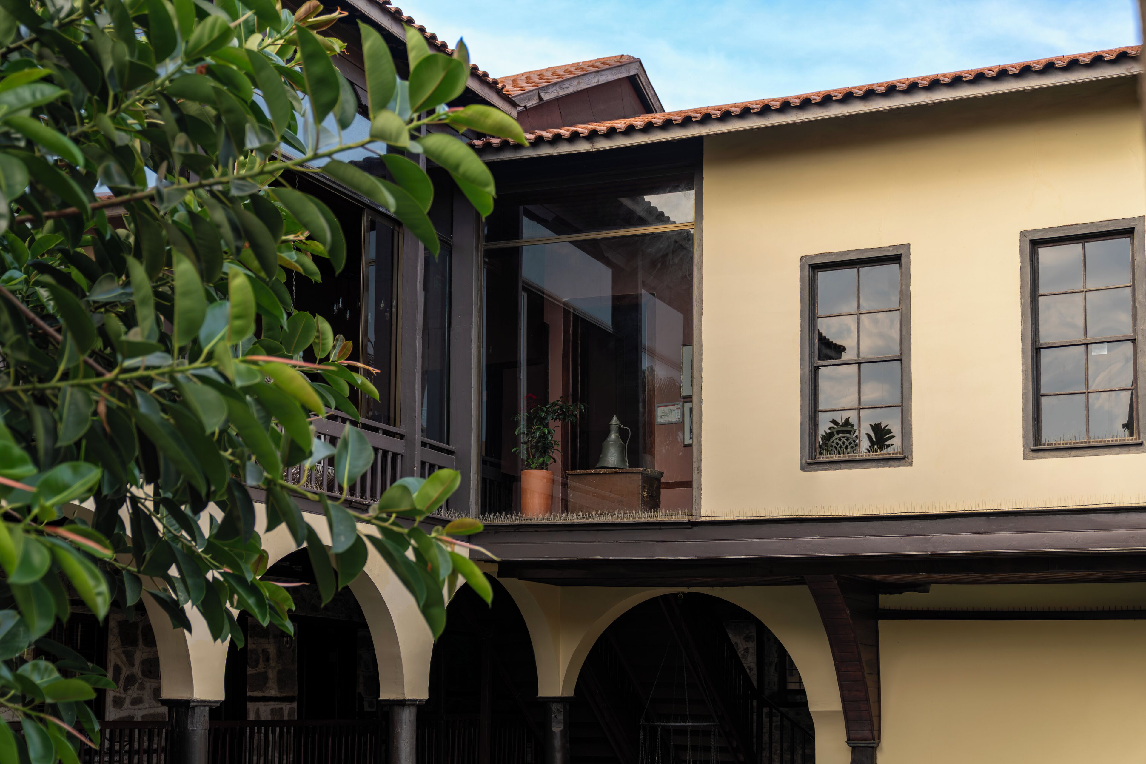 A two-story building with a balcony, large windows, and a tiled roof.