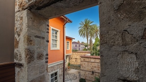 Un patio con muro de piedra, una palmera y un edificio con ventana.