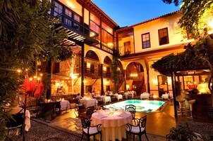A courtyard with outdoor dining tables, a swimming pool, and a bar area.