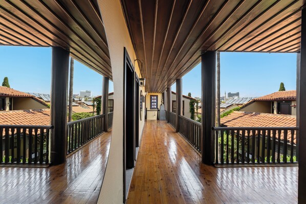 A corridor with wooden flooring and black railings, leading to balconies with tiled roofs. - Alp Pasa Hotel - Special Class (Antalya)