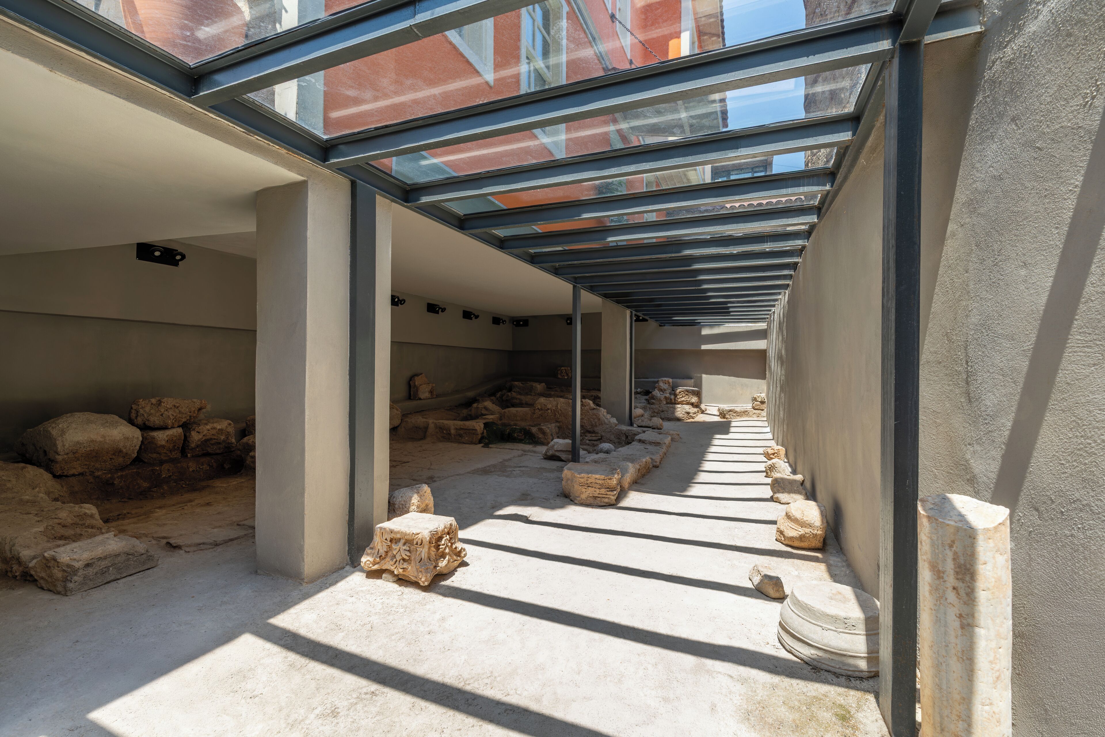 An interior with a glass ceiling, stone columns, and scattered artifacts on the floor.