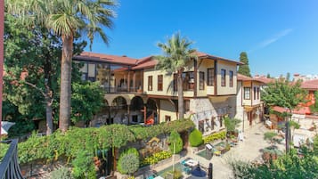 Experience the charm of a Mediterranean-style building with a tranquil courtyard, lush greenery, and arched windows.