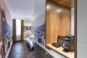A hotel room with a bed, a nightstand with a coffee machine, and a wall with a cityscape mural. - The Claremont  (Douglas)
