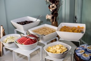 Una mesa de buffet con diversos alimentos, incluyendo frutas y postres.