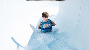 A child in a water slide area, wearing a life jacket. - Apollo Jersey (St. Helier)