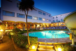 Un hôtel doté d’une piscine, d’un espace extérieur aménagé et d’une terrasse bien éclairée.