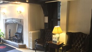 Une pièce chaleureuse avec une cheminée, un radiateur, une lampe et deux fauteuils en cuir.