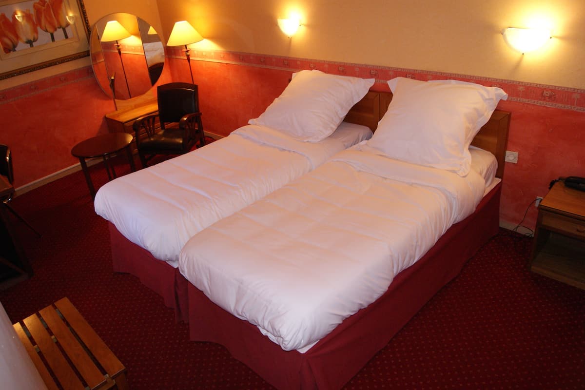 Une chambre d’hôtel avec un lit double, deux tables de chevet, une chaise, un bureau et une lampe.