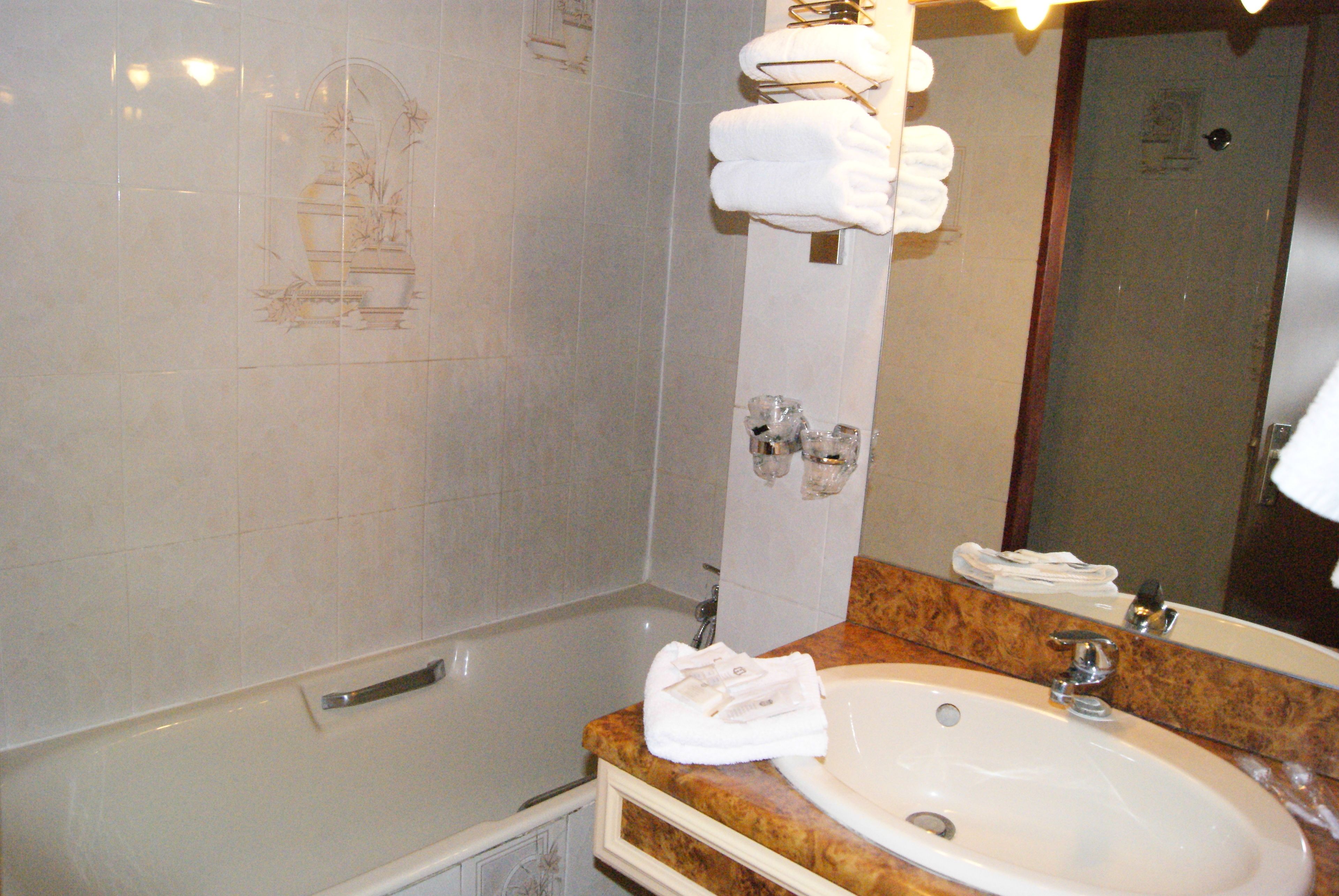Un baño con lavamanos de mármol, un espejo y un perchero para toallas.
