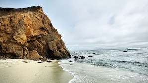 Un paisaje costero con una playa arenosa, acantilados rocosos y el océano.