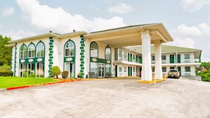 A hotel with a covered entrance, multiple windows, and a parking area. - Evergreen Inn (Branson)