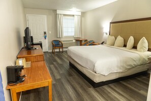 A hotel room with a bed, a desk with a computer, a chair, and a small table. - Signature Inn Branson (Branson)
