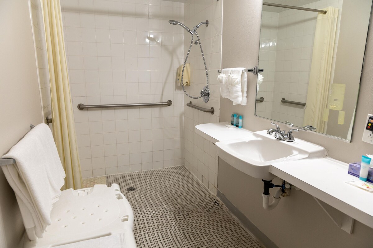 A bathroom with a shower, two sinks, a mirror, and a hand dryer.