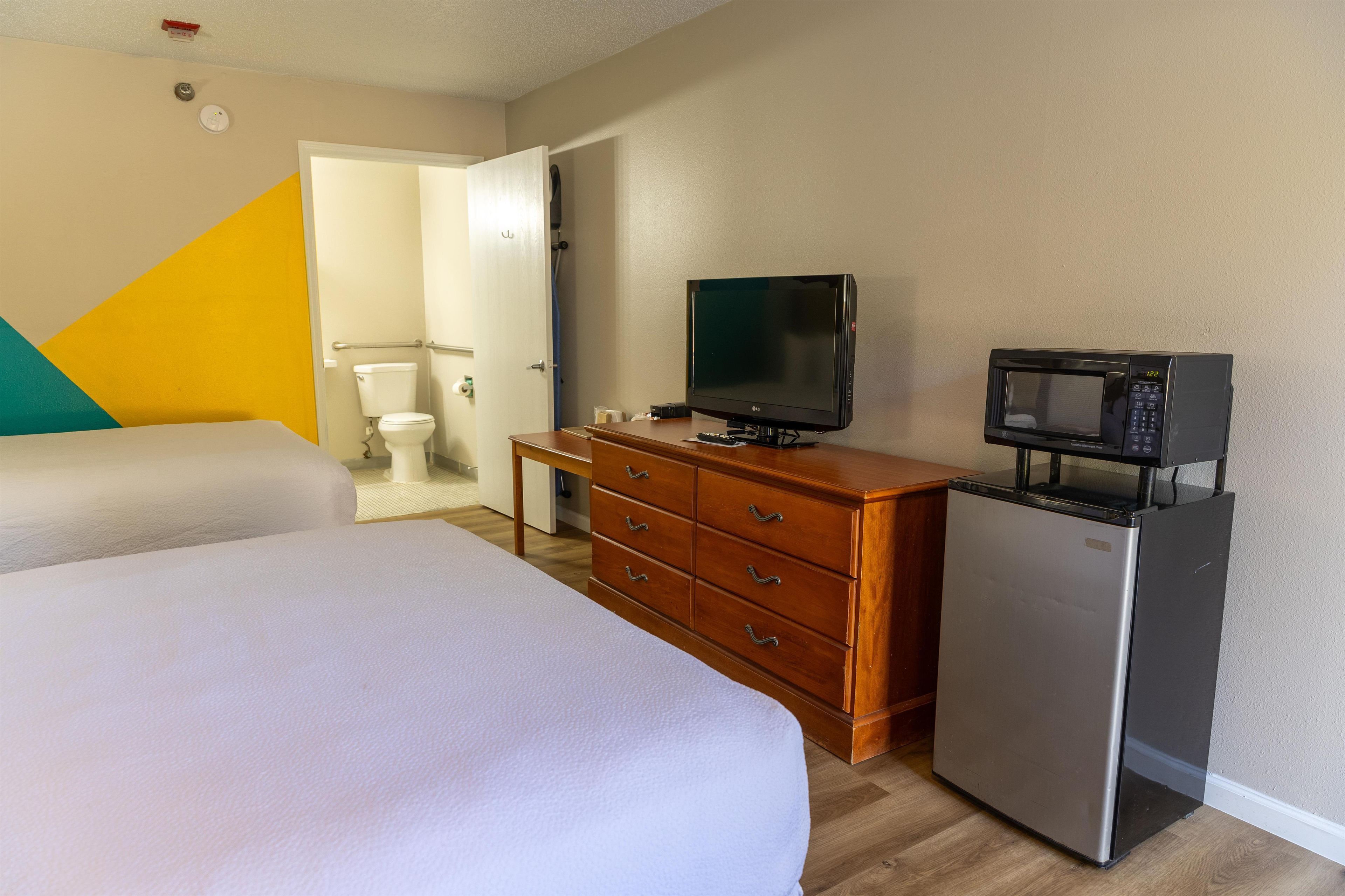 Een hotelkamer met een bed, een houten dressoir, een televisie en een koelkast.