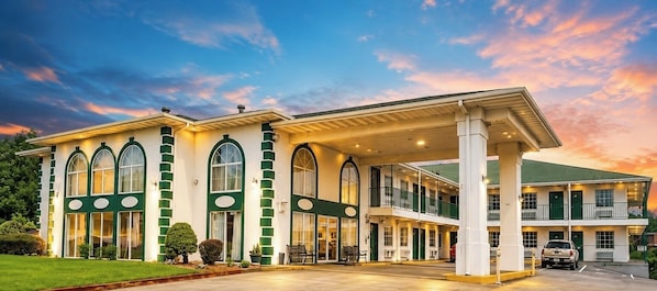 Un hotel de dos plantas, con amplias ventanas y una zona exterior cubierta.