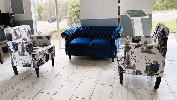 A modern living room with a blue sofa, two floral armchairs, a flat-screen TV, and a coffee table. - Evergreen Inn (Branson)