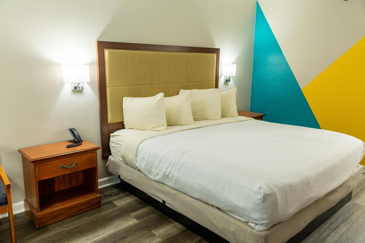 A hotel room with a bed, bedside table, and a lamp.