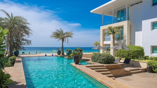 A pool area with clear blue water, palm trees, and a view of the ocean. - Paradox Resort Phuket (Karon)