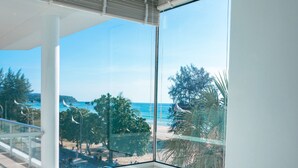A bathroom with a large bathtub, a window with a view of the beach, and a ceiling with a ventilation system. - Paradox Resort Phuket (Karon)