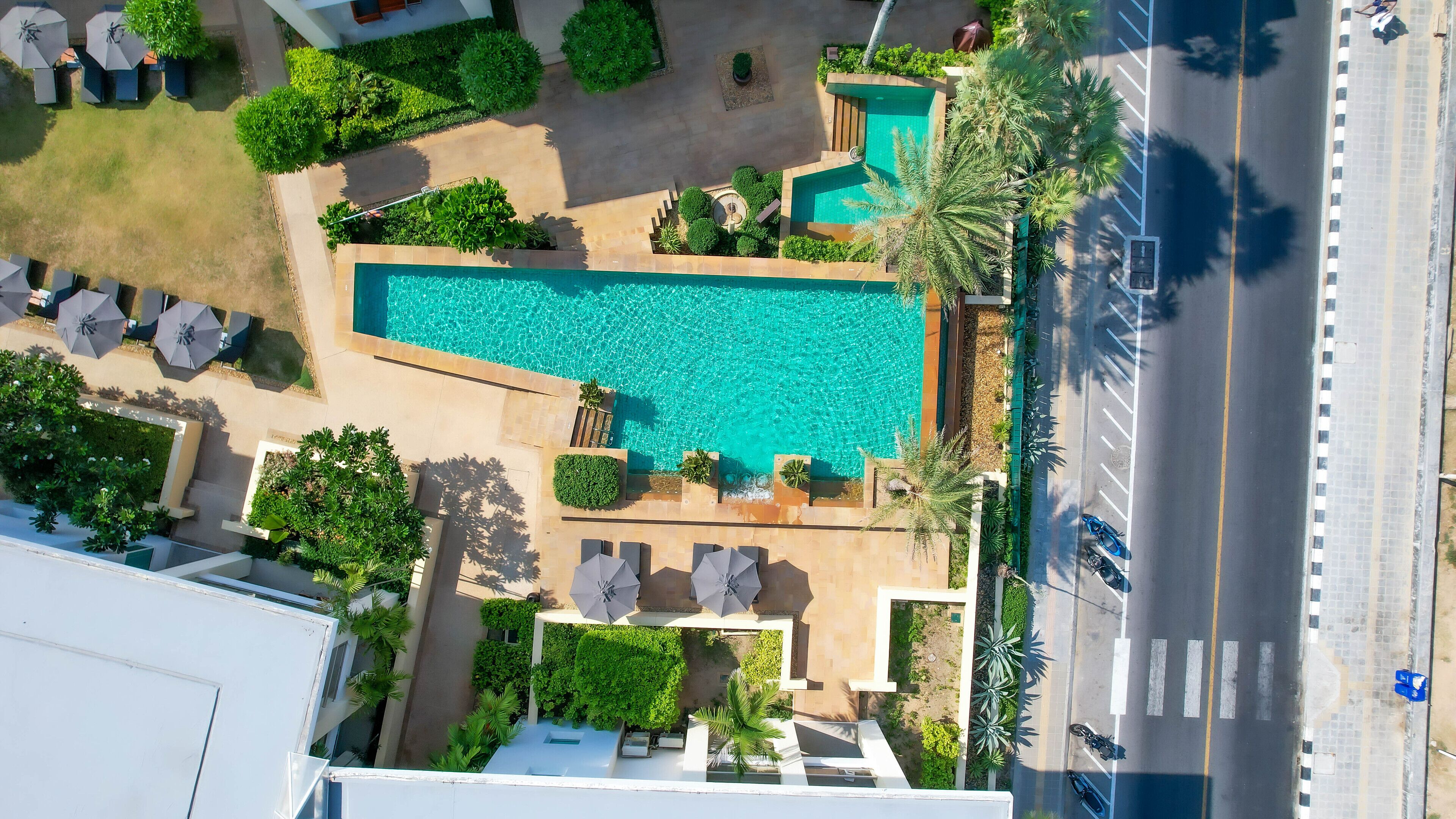 Vue aérienne d’un hôtel doté d’une piscine, d’un espace de détente extérieur et d’une route adjacente à l’établissement.