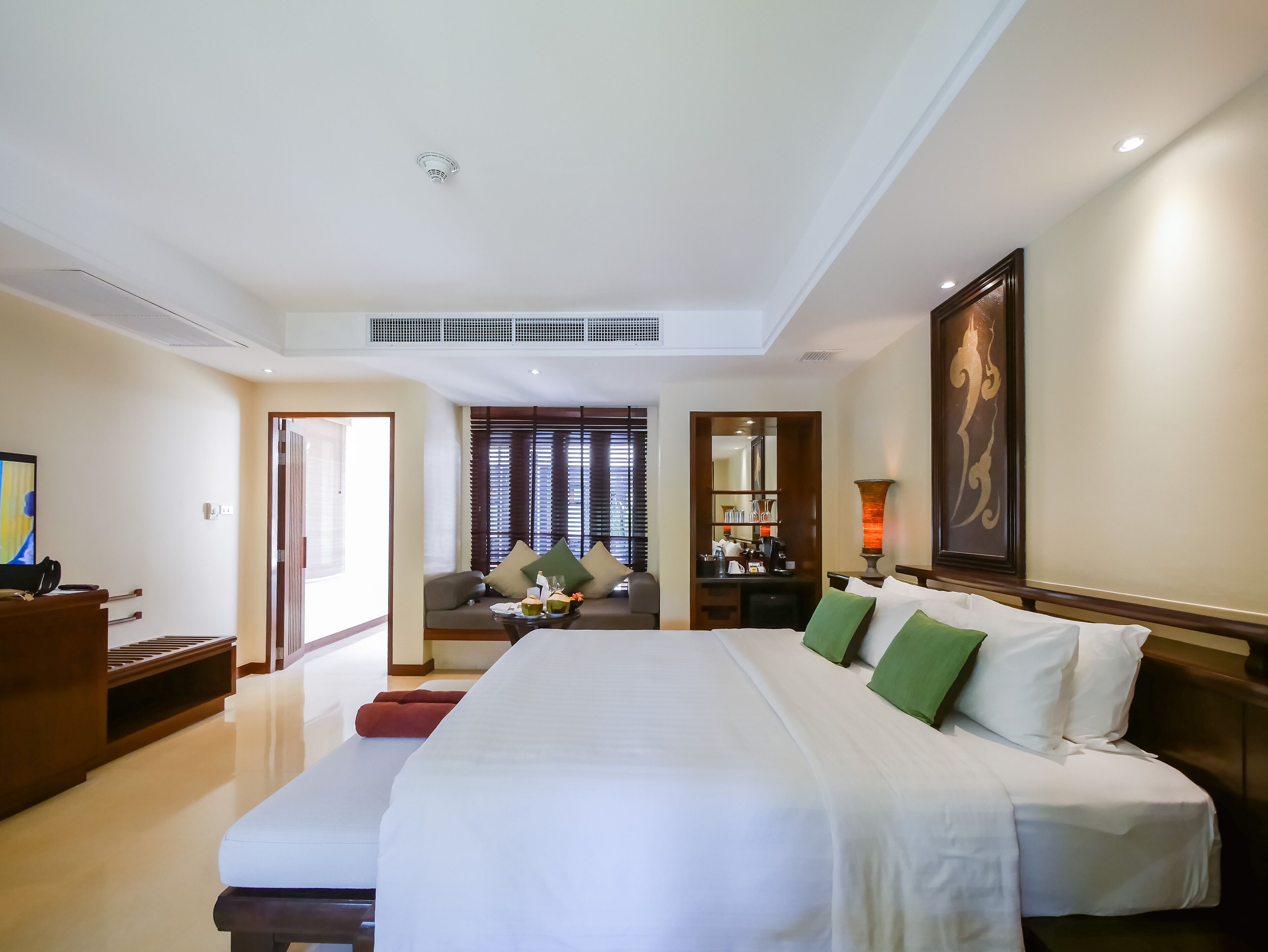 Une chambre d’hôtel avec un grand lit, un coin salon avec une table et une vue sur l’extérieur par la fenêtre.