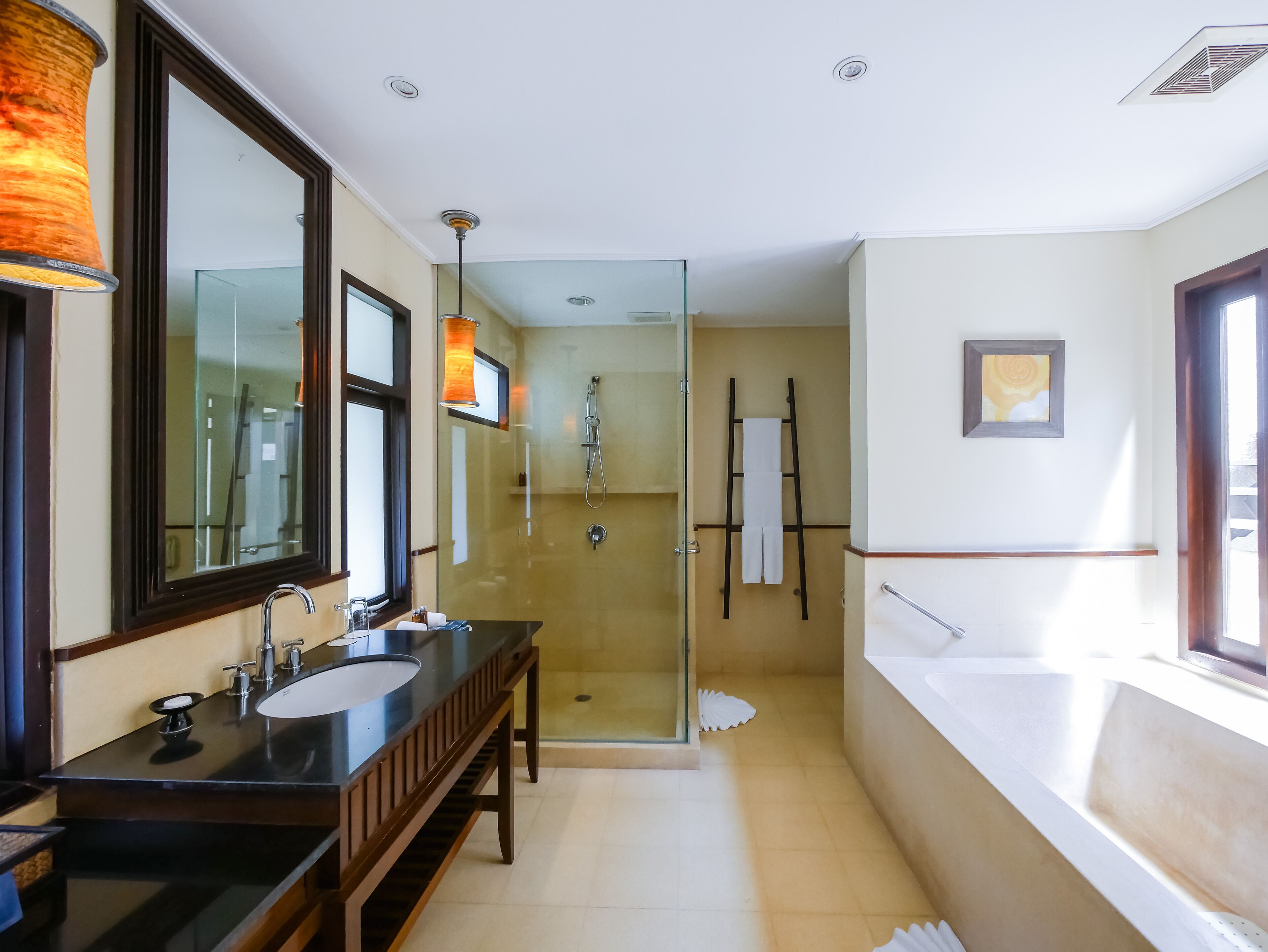 Un baño moderno con ducha acristalada, lavamanos doble y un espejo grande.
