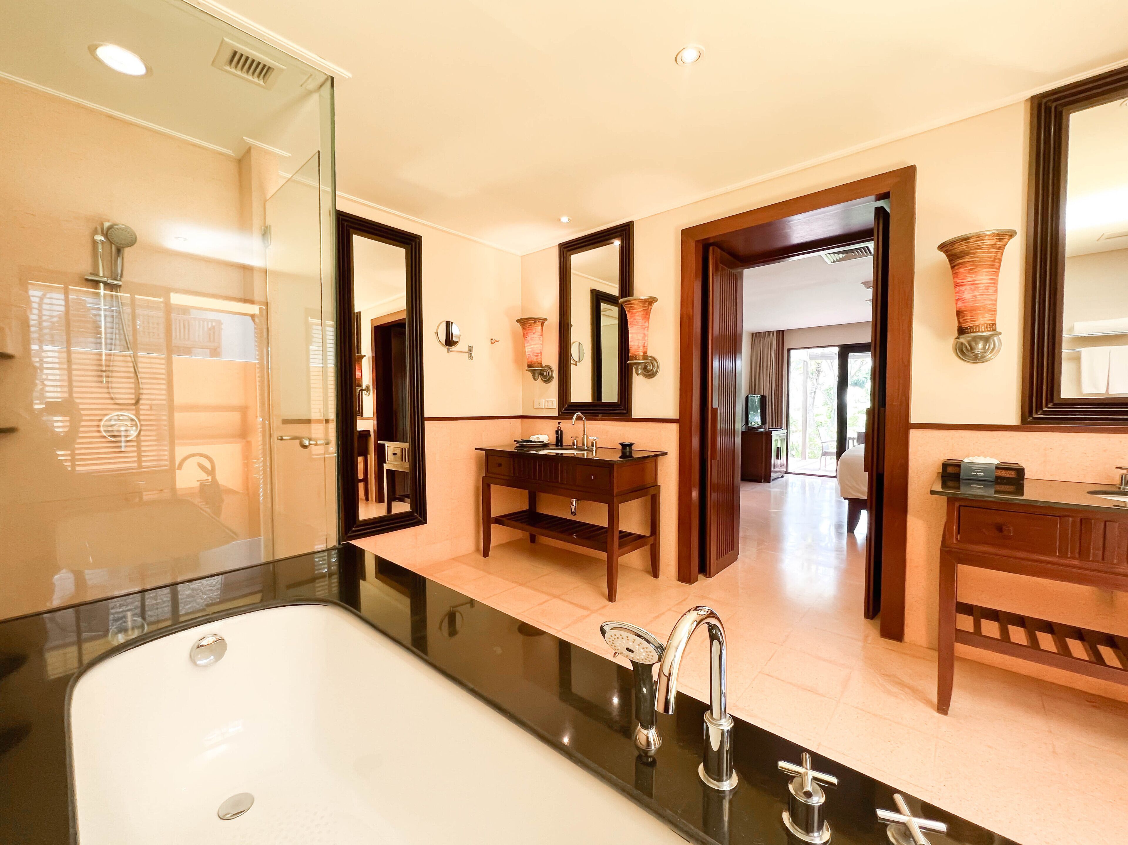 A modern bathroom with a large bathtub, a vanity with a mirror, and a shower area.