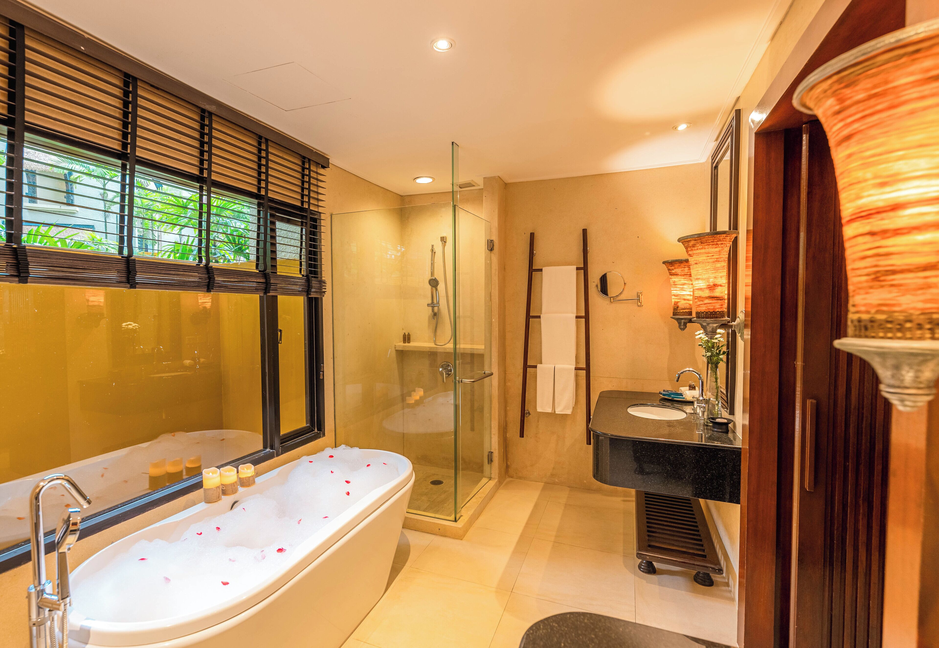A modern bathroom with a glass-enclosed shower, a freestanding bathtub, a vanity with a sink, and a mirror.