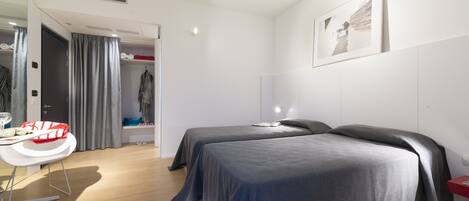 Una habitación de hotel moderna con dos camas, un escritorio y un armario.
