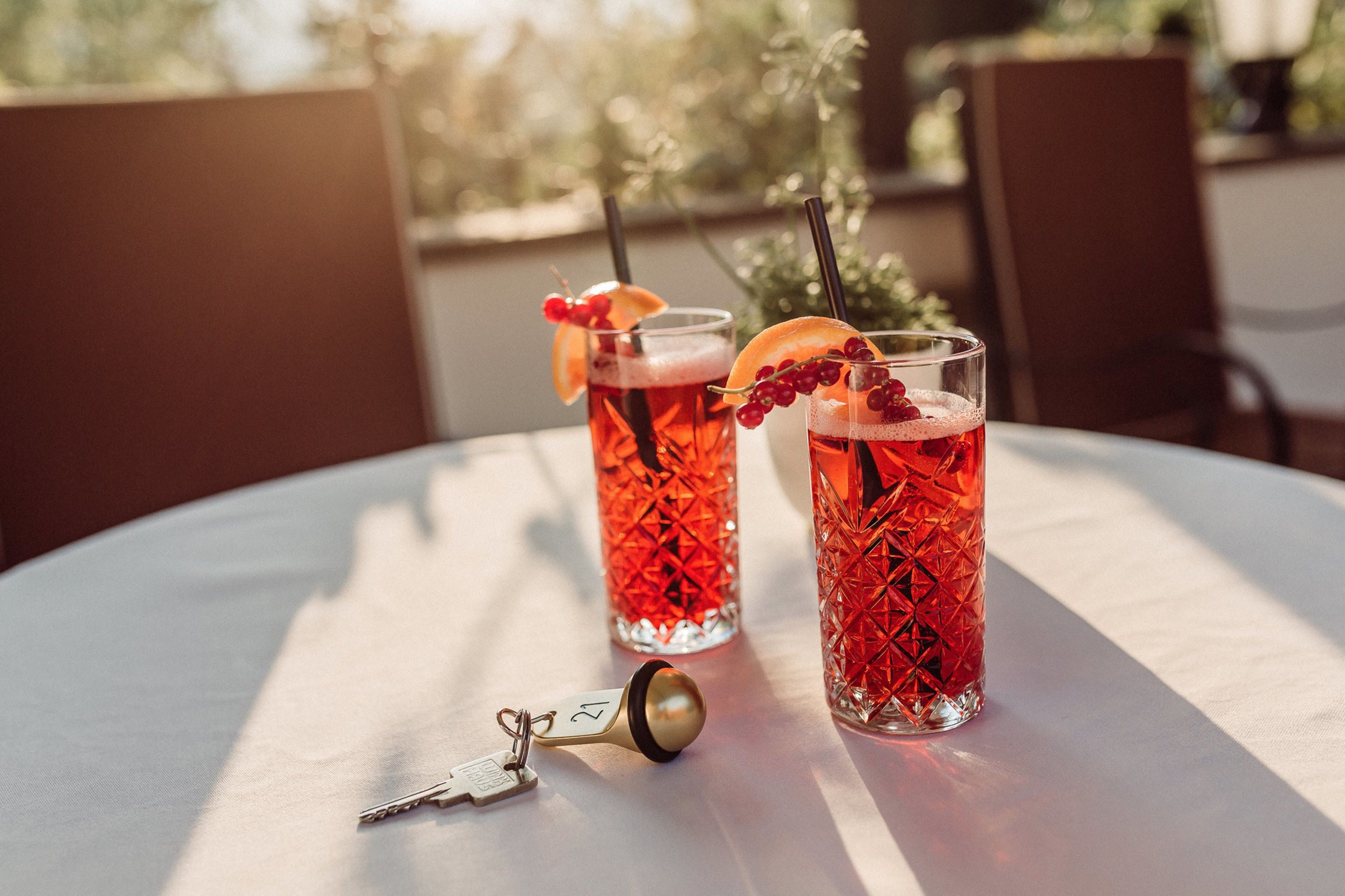 Deux verres d’une boisson rouge, garnis de quelques éléments décoratifs, sont posés sur une table.