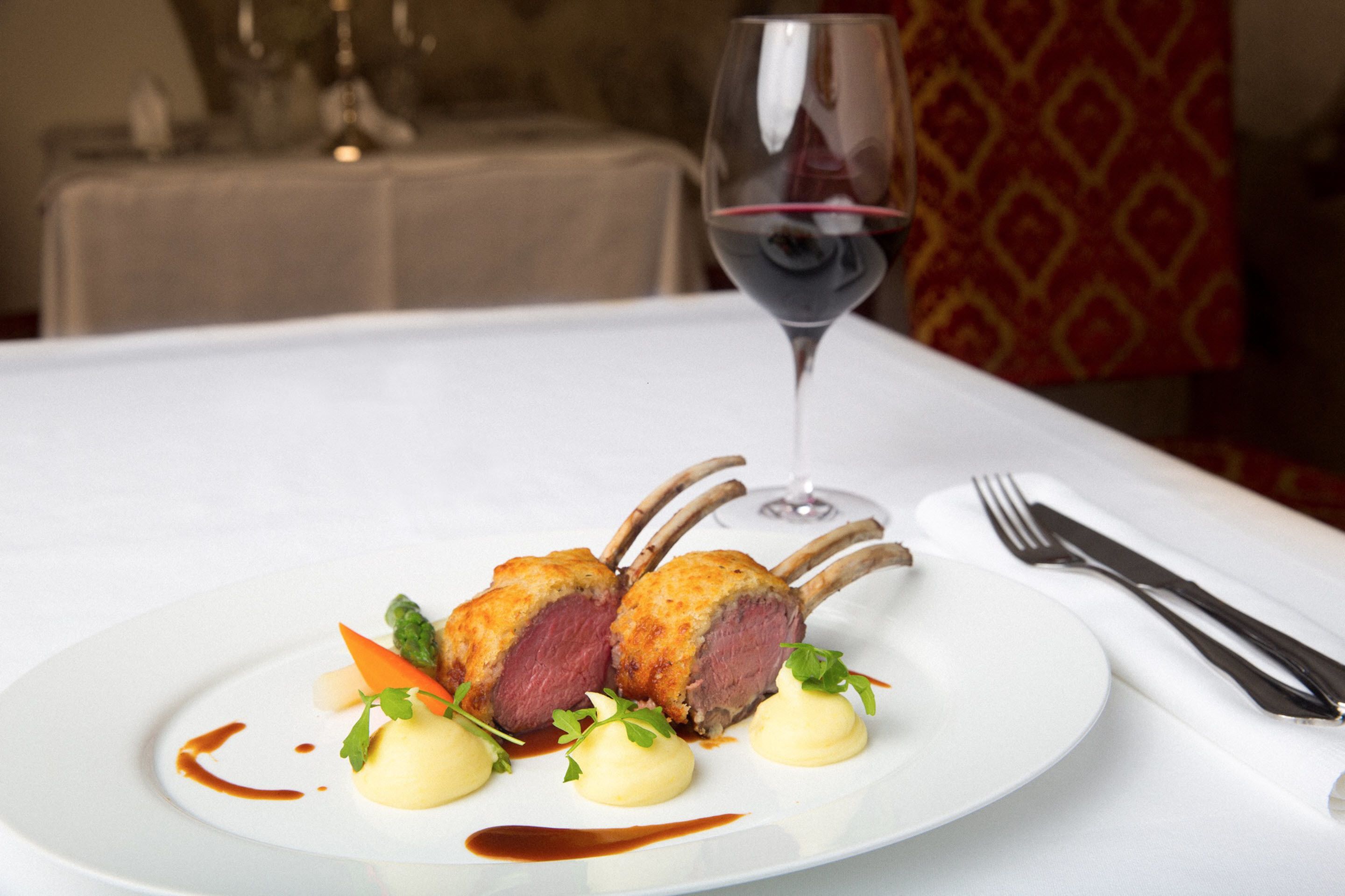 Ein Teller mit Essen und ein Glas Rotwein auf einem Tisch.