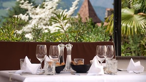 Mesa dispuesta para comer con vista a montañas y la aguja de una iglesia.