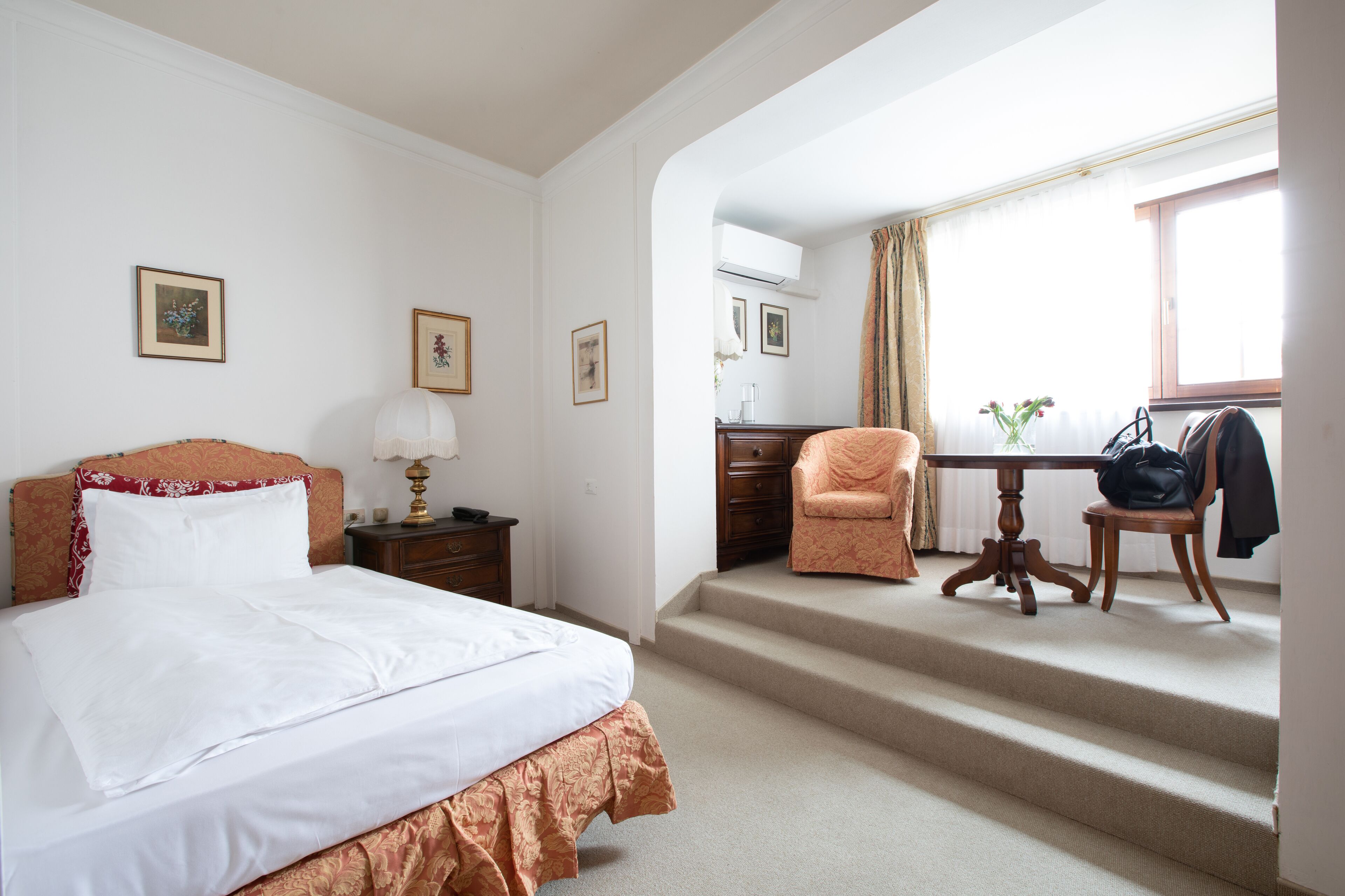 A hotel room with a bed, a desk, a chair, and a staircase.