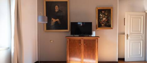 A room with a wooden cabinet, a television, and two framed artworks on the wall.