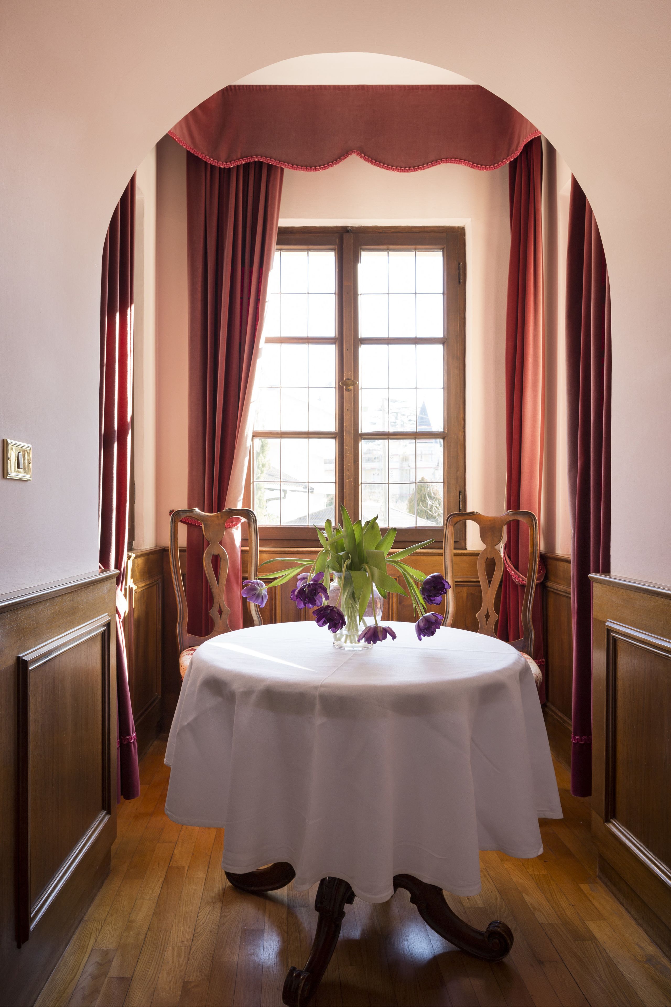 Un coin repas avec une table ronde, des chaises et une fenêtre avec des rideaux.
