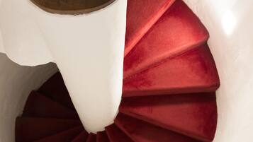 Una escalera de caracol con barandilla de madera y escalones rojos.