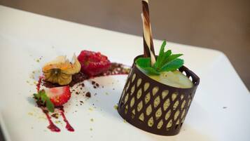 A dessert on a white plate with a chocolate cup and a strawberry.